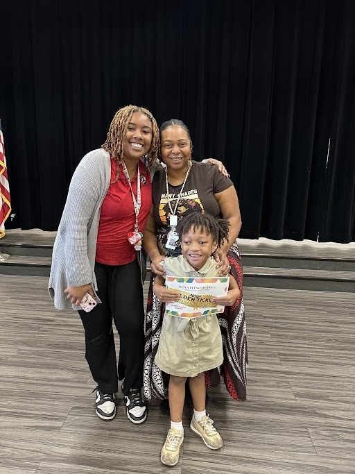 Ms. Highsmith, Mrs. Remi, and a student being recognized for student of the month