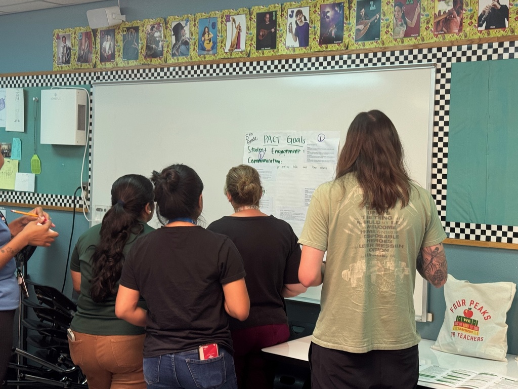 A team of people is gathered around a whiteboard, actively sharing thoughts and strategies during a meeting.