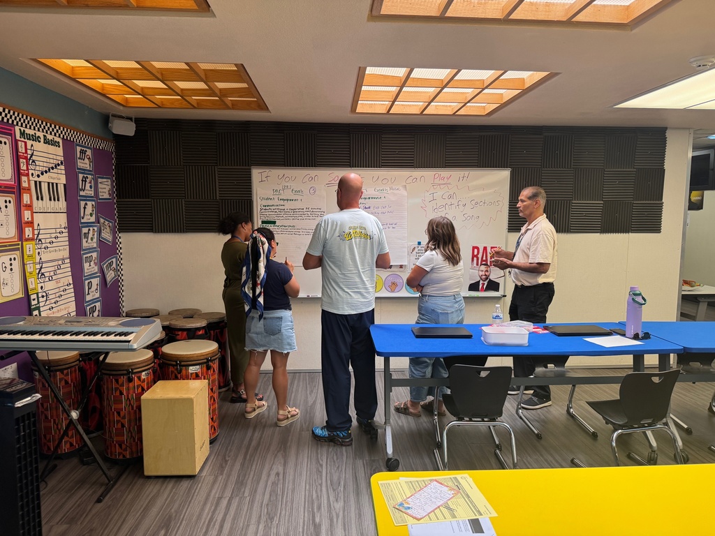 A group of people gathered around a table in a classroom, engaged in discussion and collaboration.