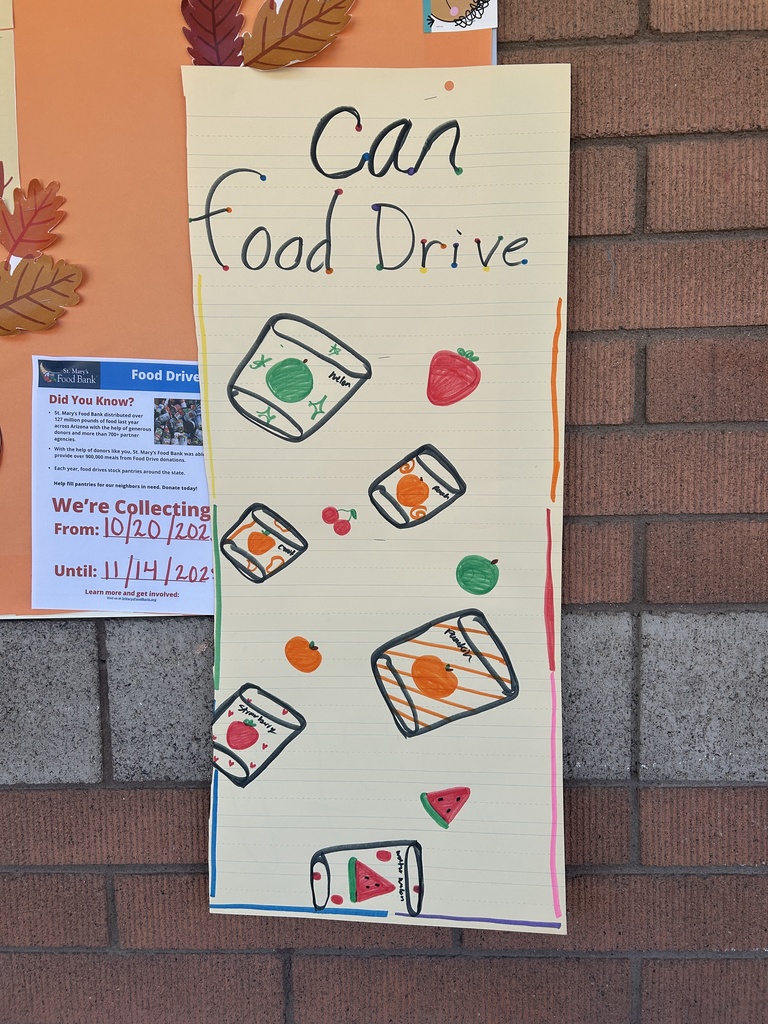 A brightly colored, student-made poster on lined yellow paper titled "Can Food Drive." It features hand-drawn illustrations of several cans of food and various fruits like strawberries, oranges, and watermelon.