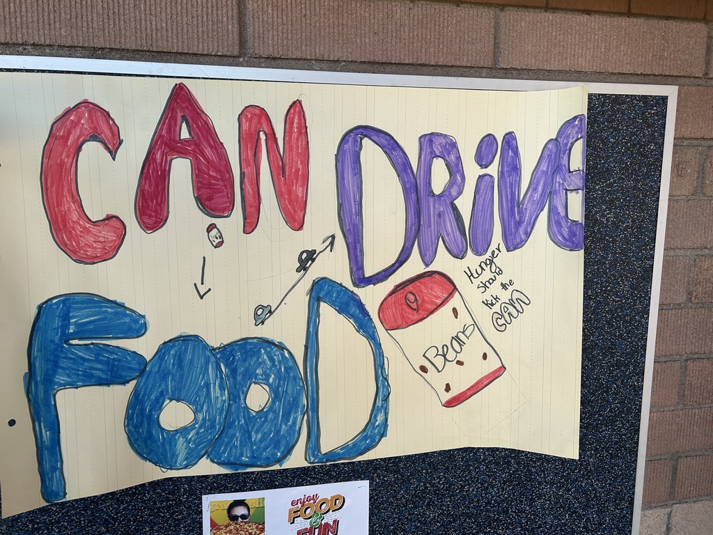 A close-up, student-made poster with the title "CAN FOOD DRIVE" in large, colorful, bubble letters. A drawing of a can of beans is featured with the handwritten phrase, "Hunger Should Kick the Can."