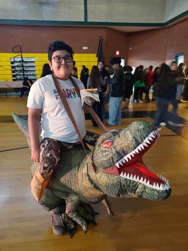 a boy wearing an inflatable costume that makes it look like he is riding a t-rex 