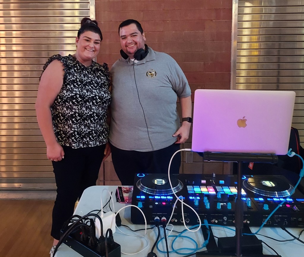 Two teachers stand in front of a DJ booth