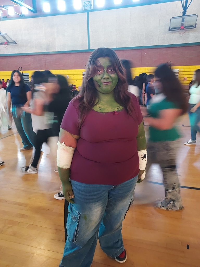 A girl with green-painted skin and zombie make-up poses for a photo