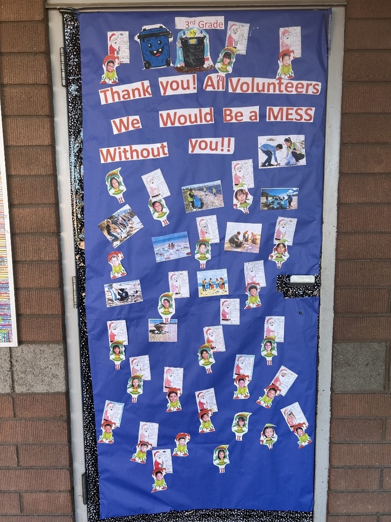 A door covered in blue paper with the message: "Thank you! All Volunteers We Would Be a MESS Without you!!" The word "MESS" is written in red. There's a small drawing of a blue recycling/trash bin with a tiny Santa hat. The rest of the door is covered with small photographs of people volunteering and small drawings of children dressed in elf outfits.