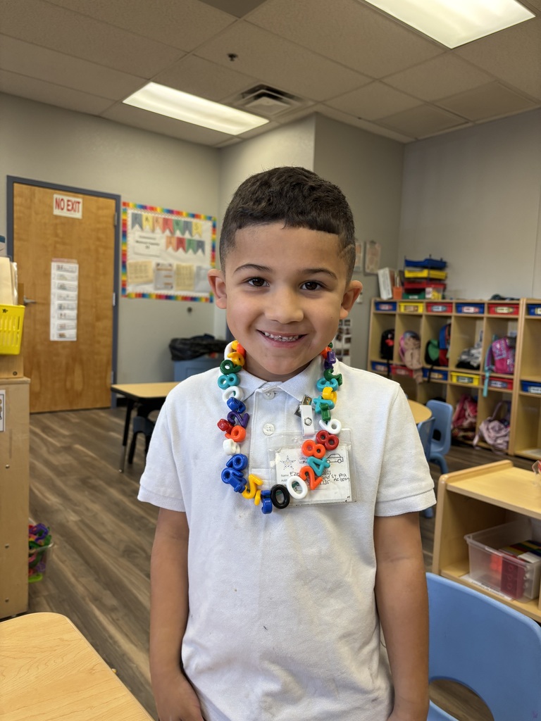 Boy wearing white shirt and necklace made of plastic numbers he strung together