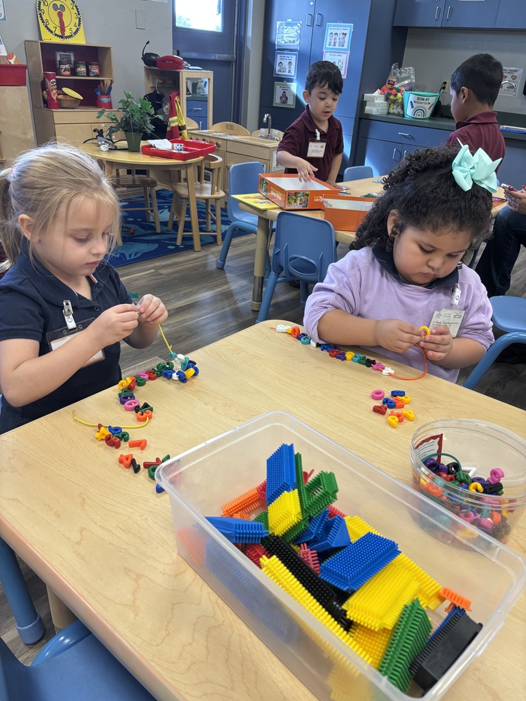 Two girls sitting at a table working on a fine motor activity