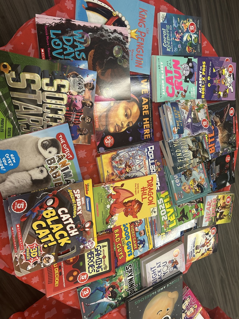 A variety of $3 and $5 "Hot Deal" books spread across a red star-patterned tablecloth. Titles include Spidey and His Amazing Friends, Dragon Hill, and Soccer Stars.