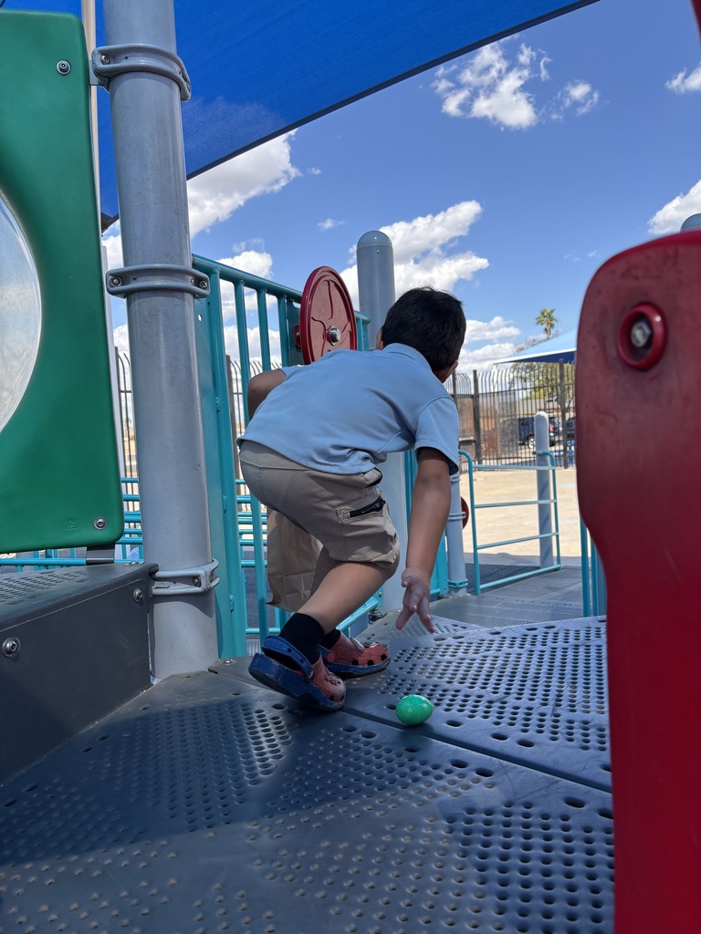 Boy picking up Easter egg on playground