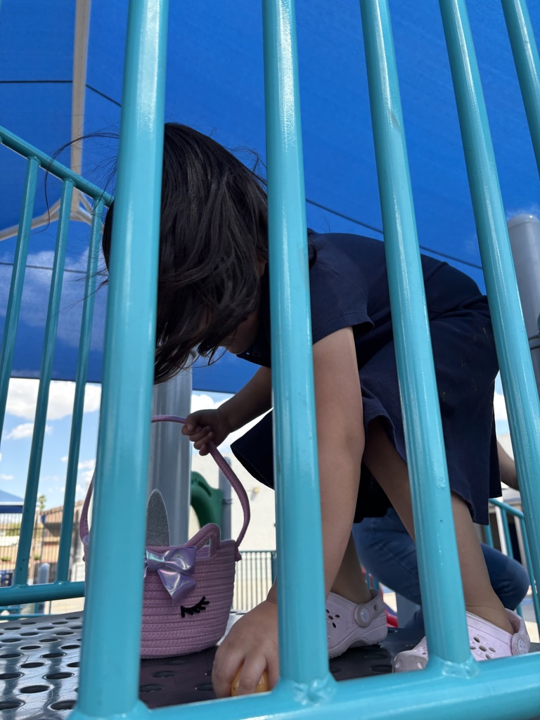 Girl picking up Easter egg on playground