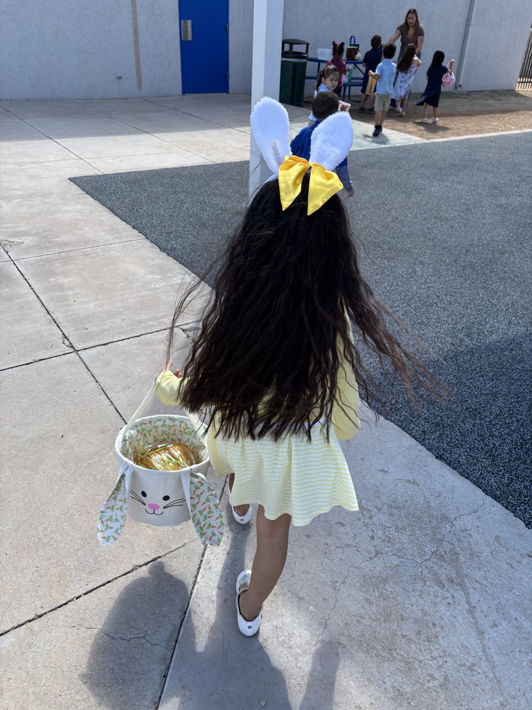 Girl wearing bunny ears walking away with her bunny easter basket  in hand