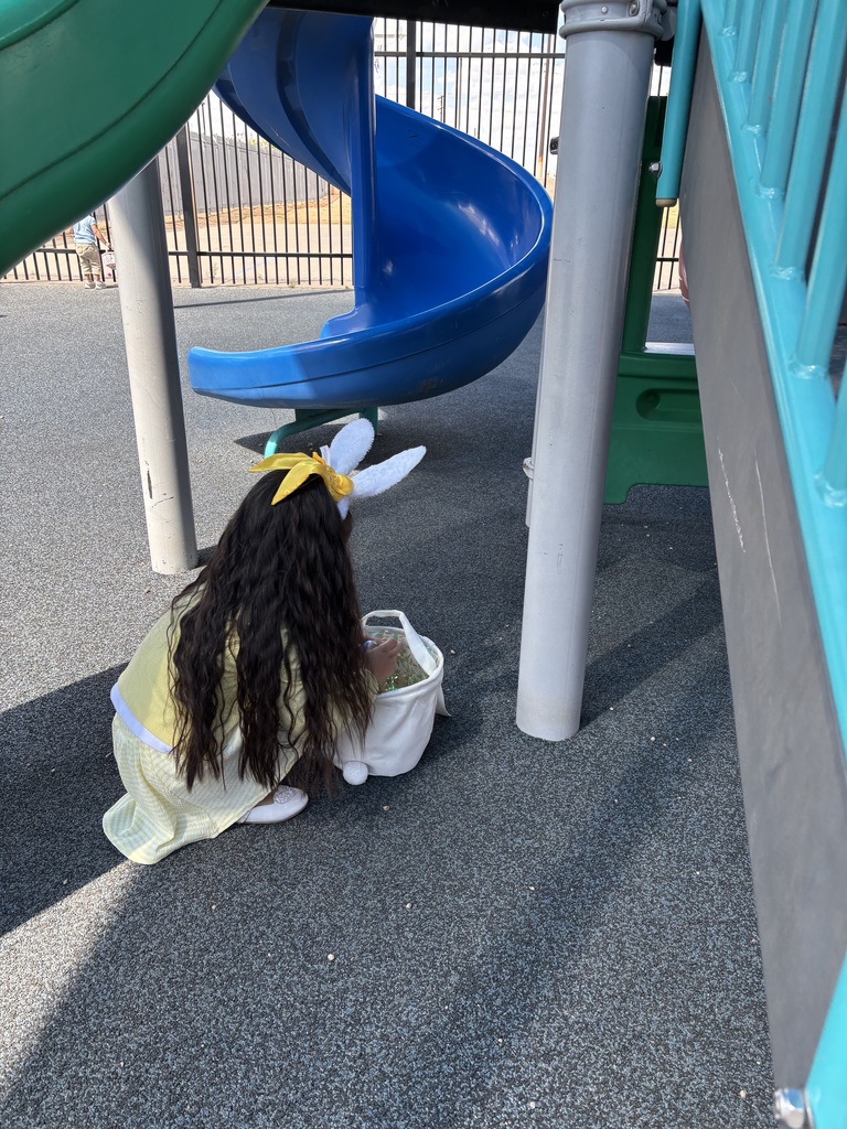 Girl picking up Easter egg on playground