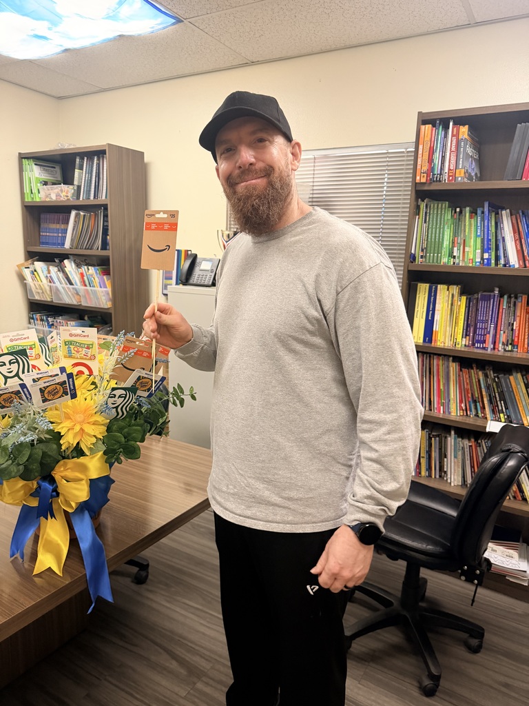 Man with a red beard and black cap holding an Amazon card.