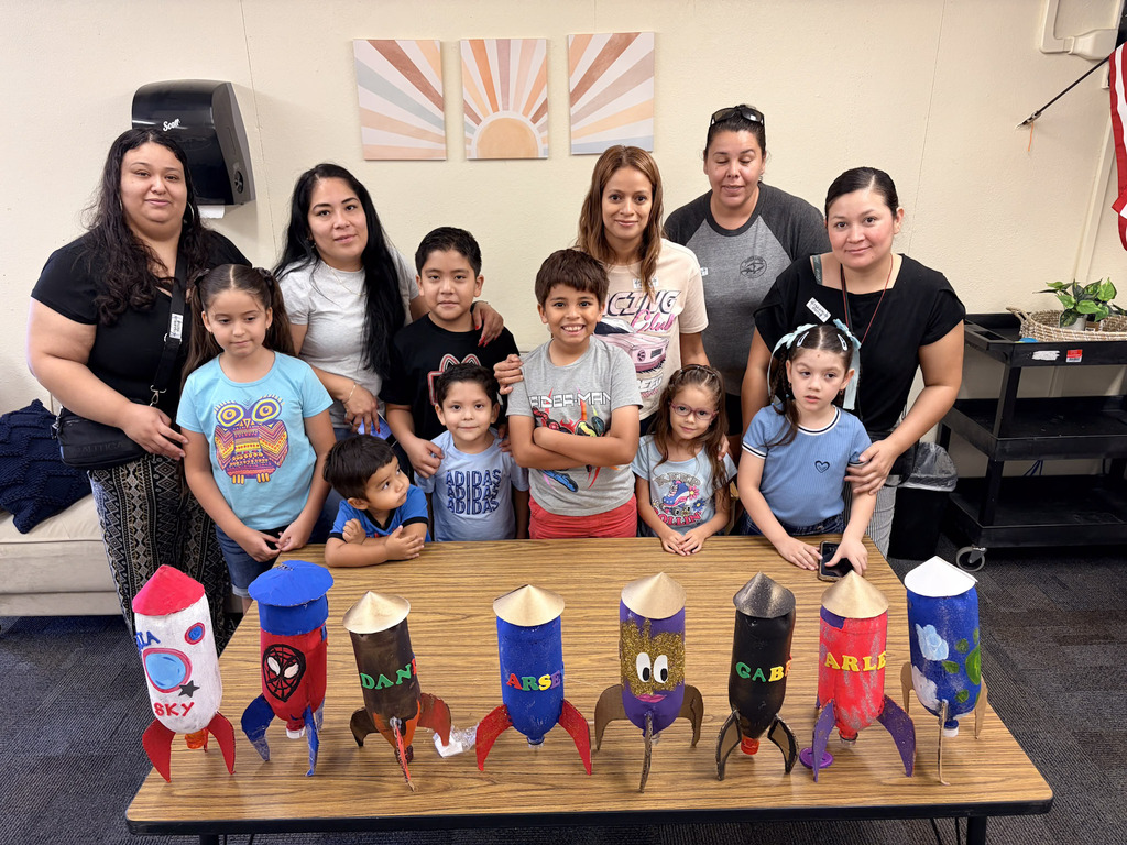 Families and students posing behind their homemade rockets