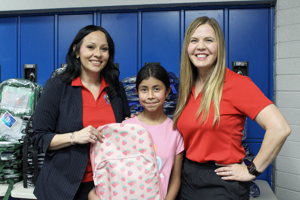 Sylvia Carrizoza, Executive Director of Employee Relations, Dr. Robertson, Principal of Esperanza Elementary posing with a student holding a backpack