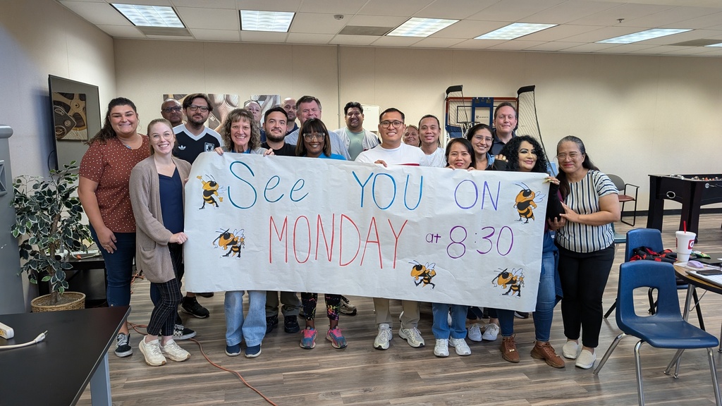 Staff posing for a photo holding a sign that says "see you on Monday at 8:30"