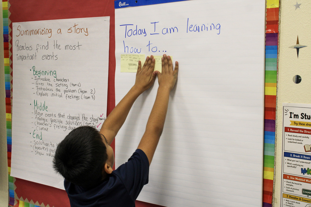 Student Holding up Sticky note to wall