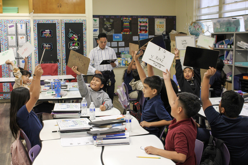 Students in math class holding up white boards