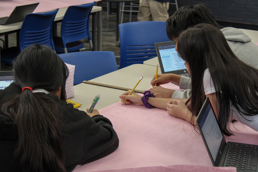Students in Mr. Bennett's Class doing work on a pink poster