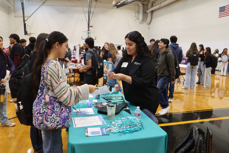 A representative from Palo Alto College talks with a student