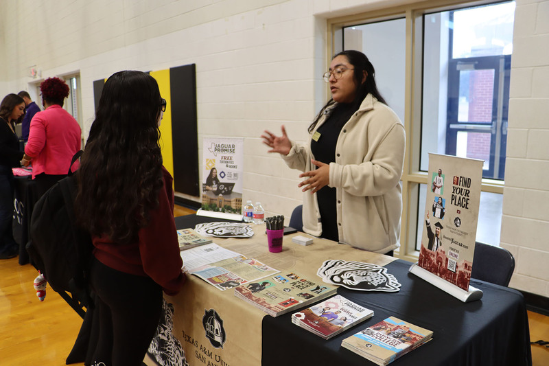 A representative from Texas A&M San Antonio talks with students