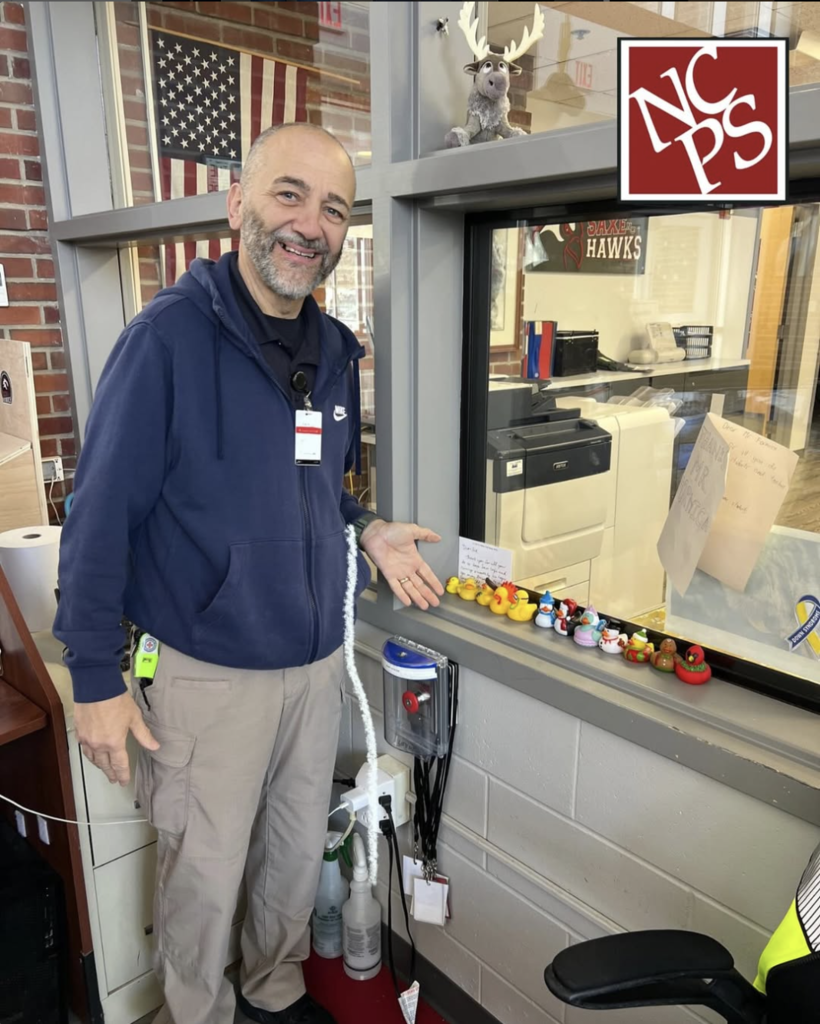 Sid gesturing to a row of rubber ducks