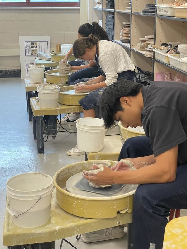 students working on clay wheel while exploring curiosity