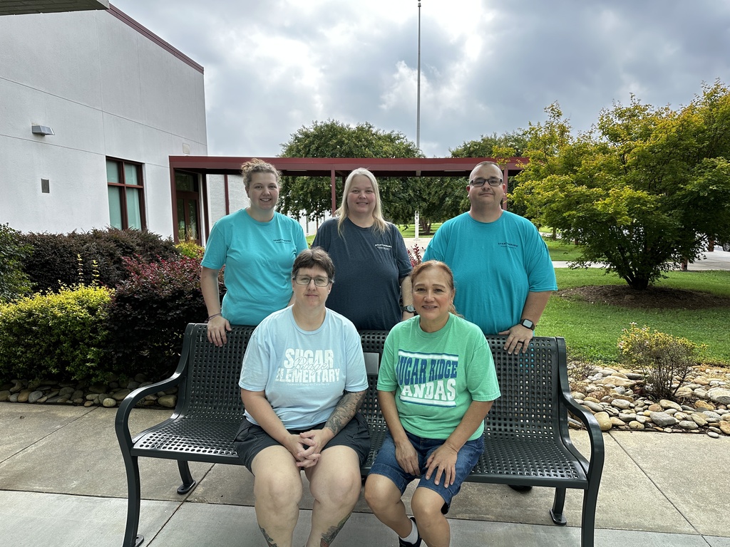Custodians on and around a bench.