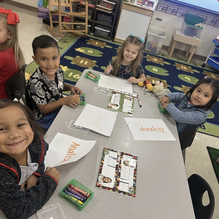 Students at table with paper and crayons.