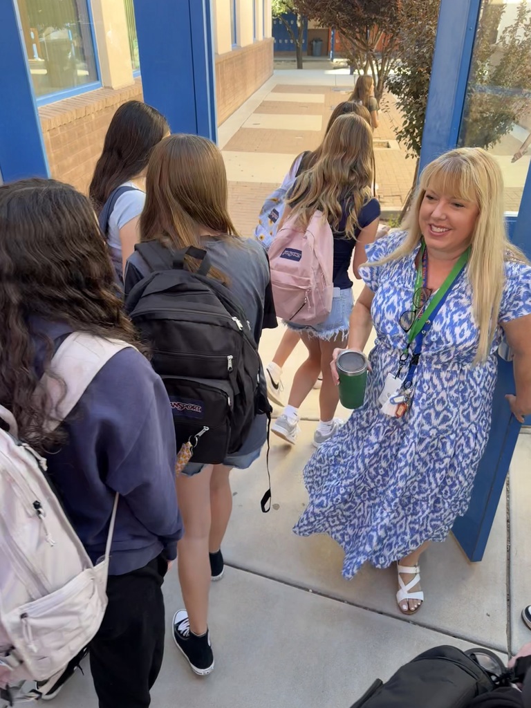 students walking into EGJH with Mrs. Egan at the door greeting students