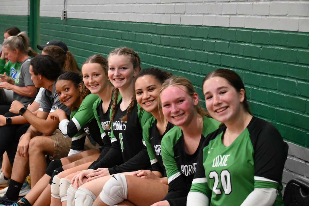 Volleyball Players sitting on bench smiling.