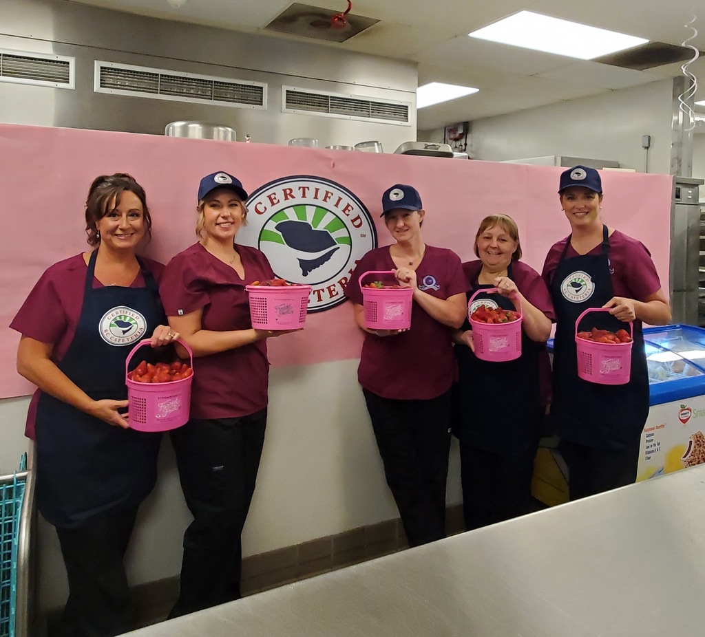 cafeteria workers posing with baskets of strawberries