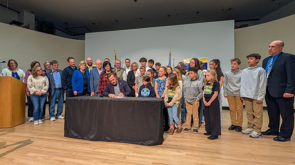 Gov. Rhoden signing a bill surrounded by local, state, and district officials as well as students from Holgate and C.C. Lee