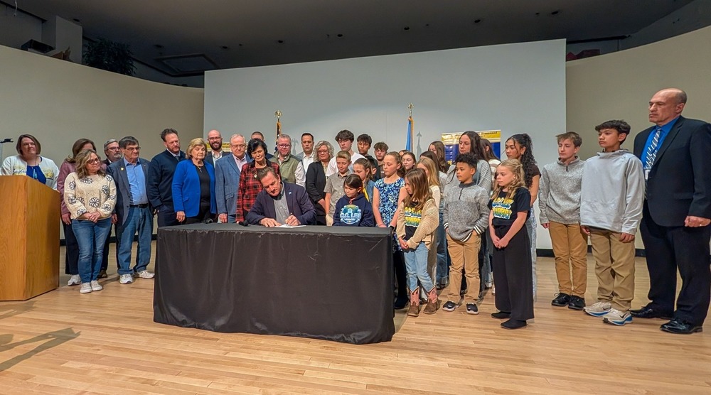 Gov. Rhoden signing a bill surrounded by local, state, and district officials as well as students from HMS and CCL