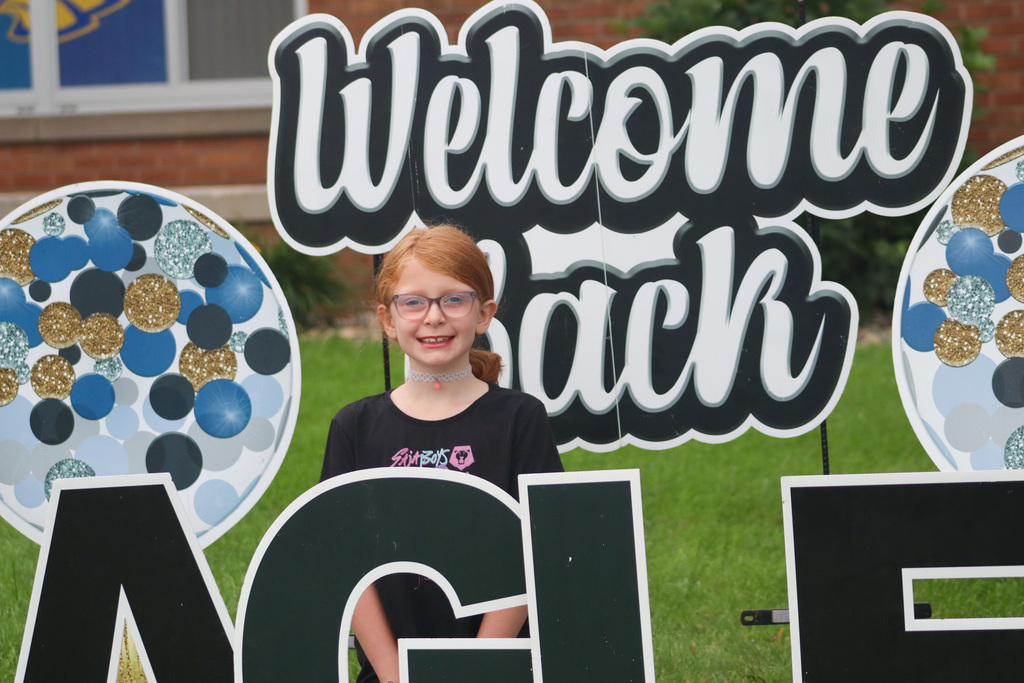 A May Overby student standing by the "Welcome Back" sign outside the school
