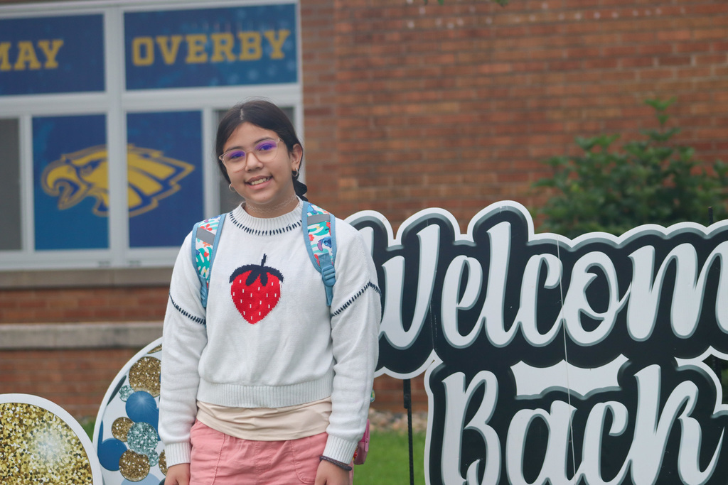 A May Overby student standing by the "Welcome Back" sign outside the school
