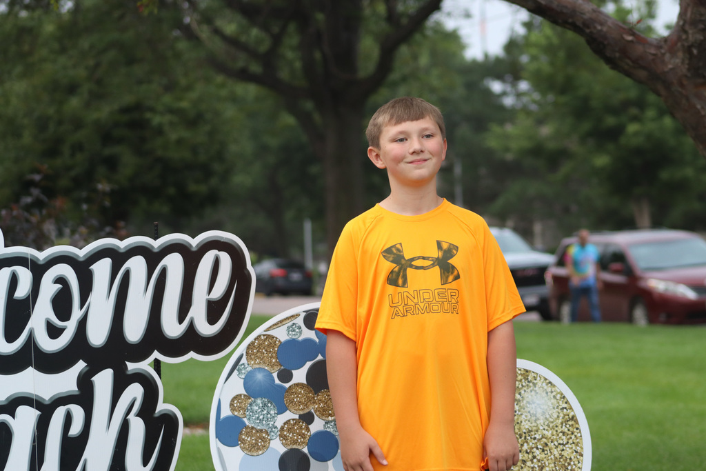 A May Overby student standing by the "Welcome Back" sign outside the school