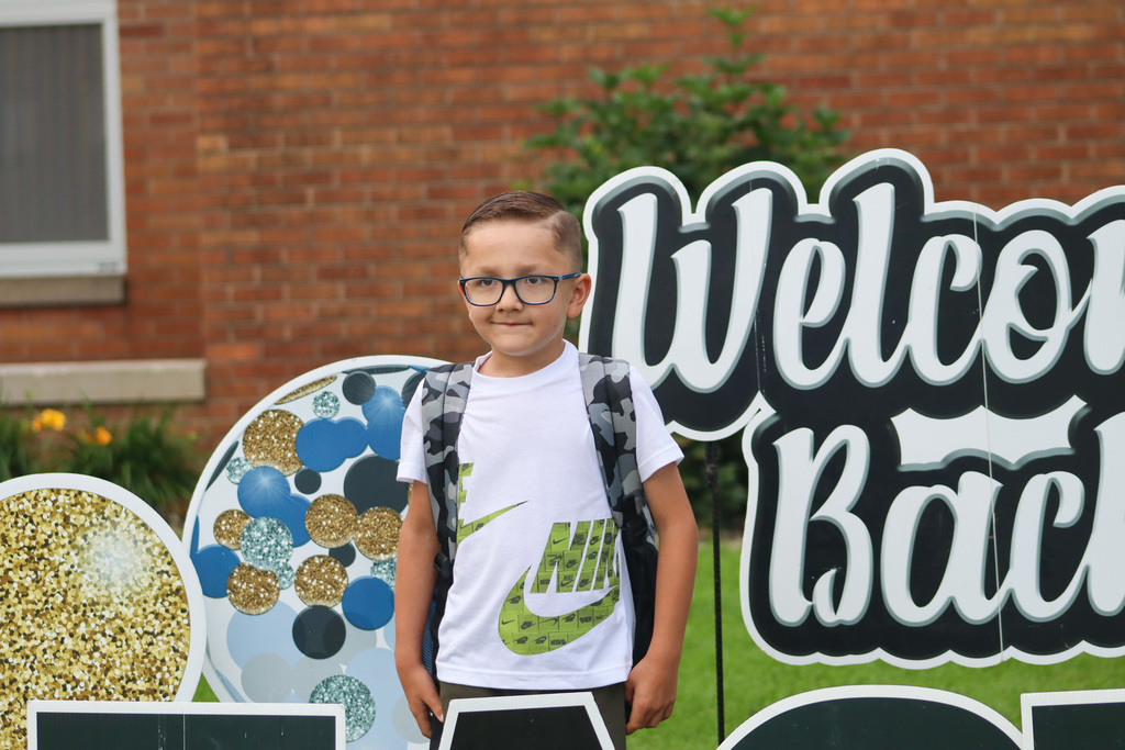 A May Overby student standing by the "Welcome Back" sign outside the school