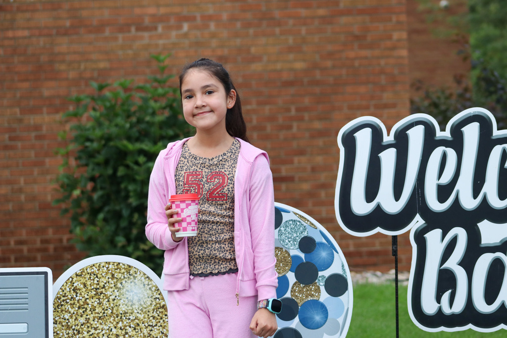 A May Overby student standing by the "WelcA May Overby studeA May Overby student standing by the "Welcome Back" sign outside the schoolnt standing by the "Welcome Back" sign outside the schoolome Back" sign outside the school
