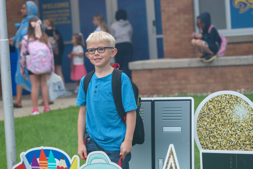 A May Overby student standing by the "Welcome Back" sign outside the school