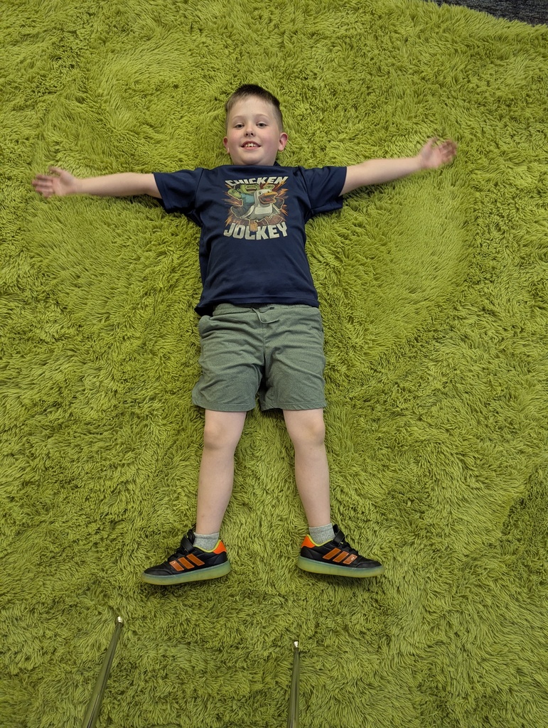 Student making a 'snow angel' on a carpet at Simmons Elementary