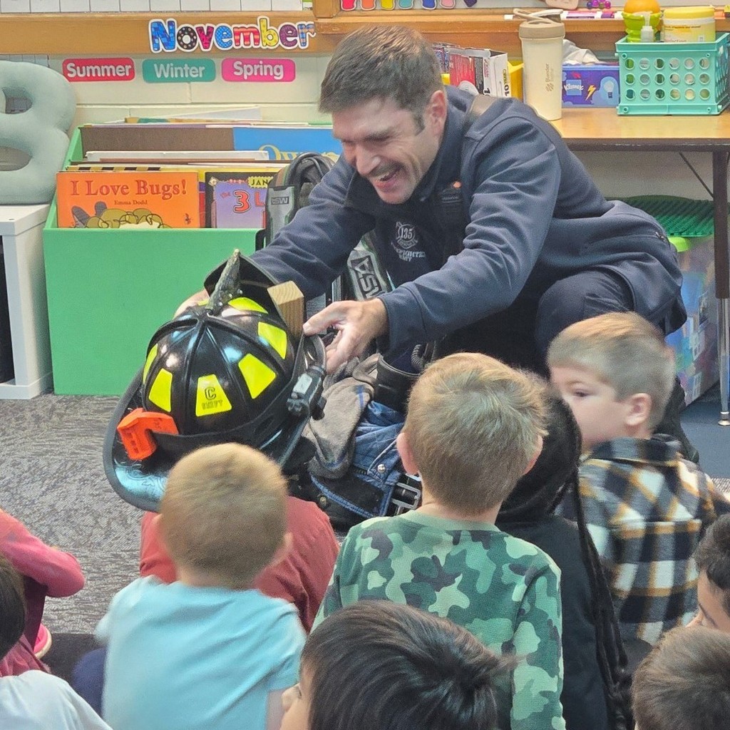 firefighters helping student try on helmet