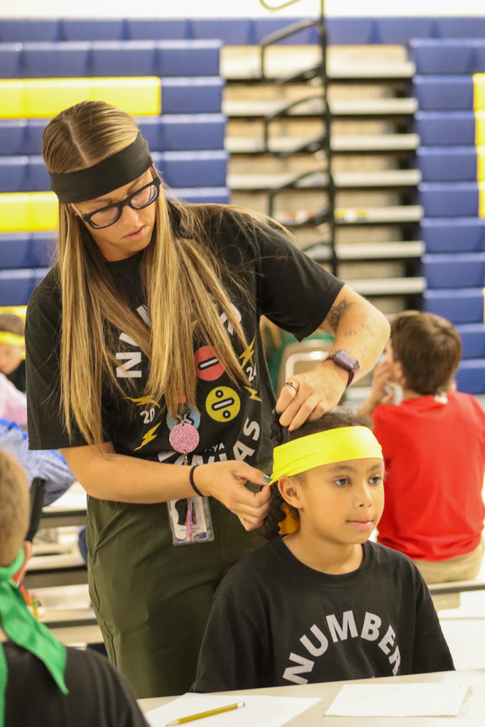 A teacher helping a Number Ninjas student with her headband
