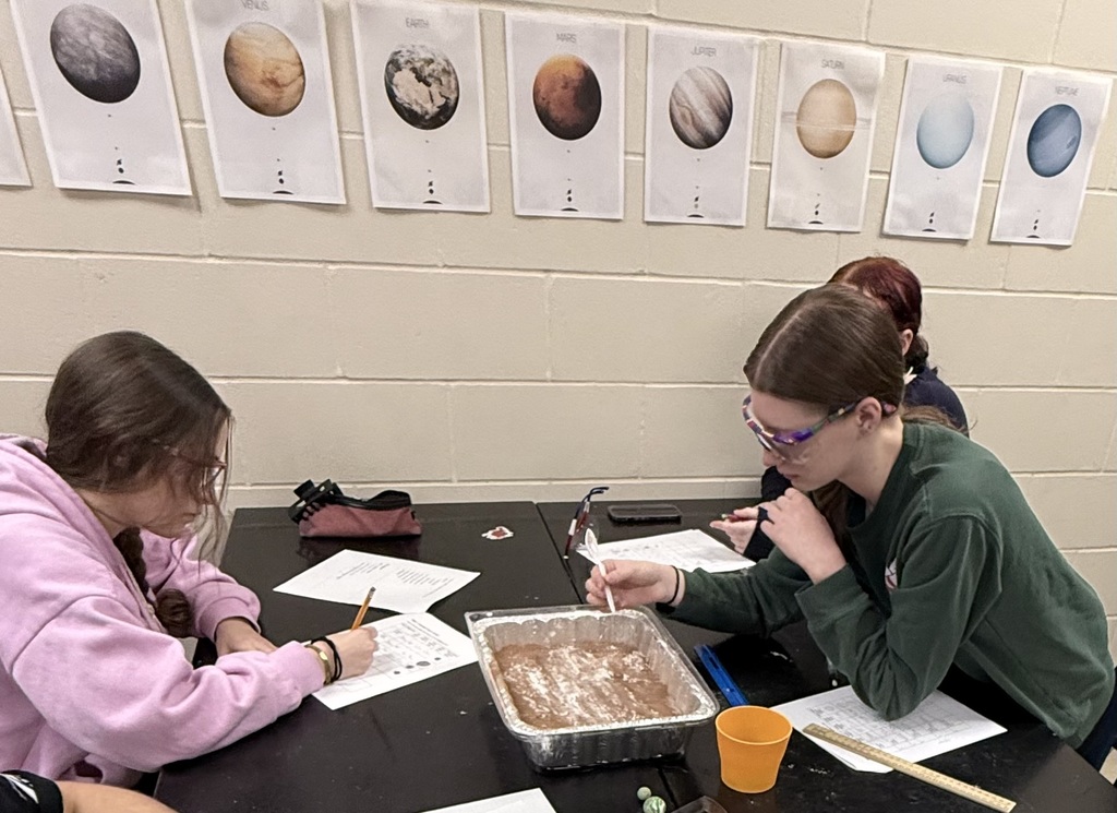 Verifying measurements with meter sticks to ensure accurate crater analysis.