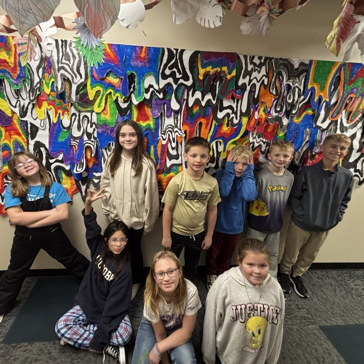 Students pose in front of artwork