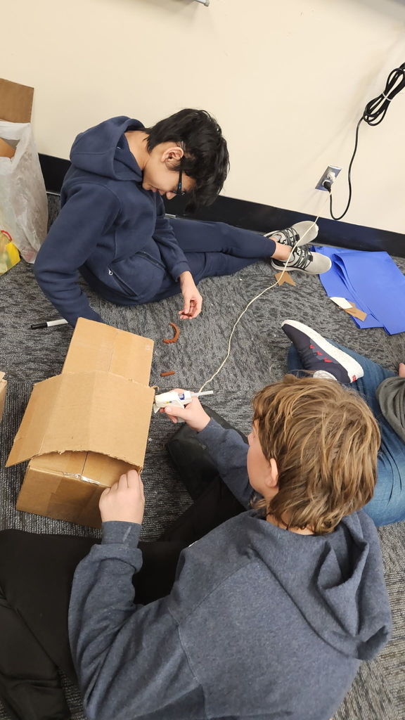 Students in Ms. Gross’ class are wrapping up their Descriptive Writing Unit with a creative culminating activity! Working in pairs, students became real estate agents for Reindeer Realty, writing vivid descriptive paragraphs to “sell” their gingerbread houses.  To bring their writing to life, students designed and built their gingerbread houses using cardboard and other materials, focusing on details that matched their descriptions.  On Friday, 6th and 7th grade students will tour the neighborhood and “purchase” the houses that best match the written descriptions. This engaging project combines creativity, collaboration, and strong writing skills—and it’s been a huge hit! 🎄🏠✏️