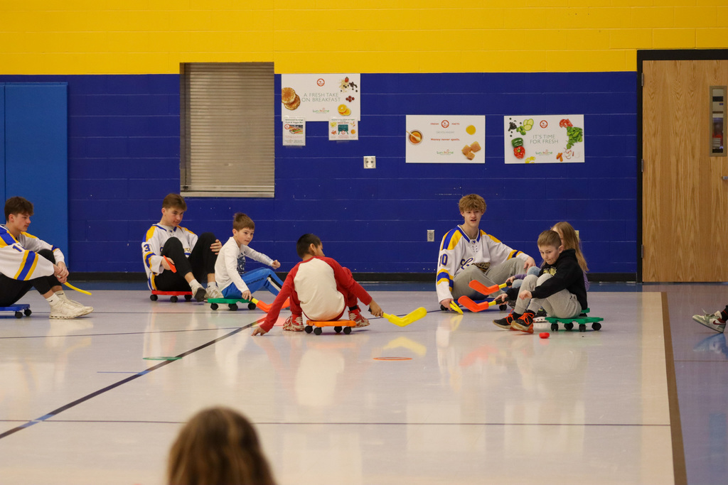 C.C. Lee students playing scooter hockey with Aberdeen Cougar Hockey players