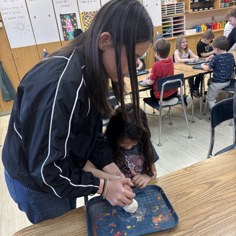 5th-graders help Kindergarten students with their pinch pots.