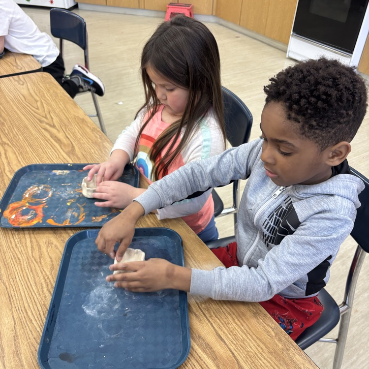 5th-graders help Kindergarten students with their pinch pots.