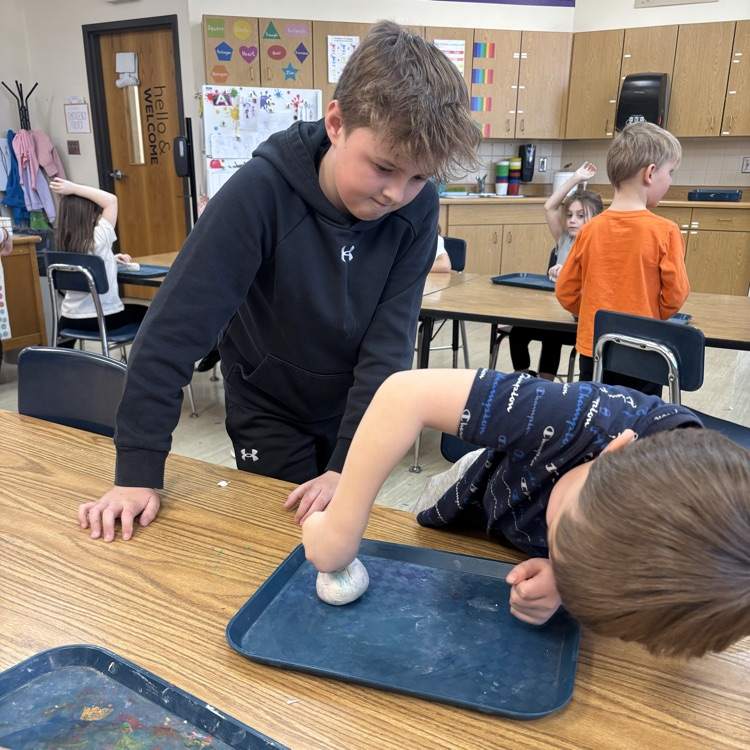 5th-graders help Kindergarten students with their pinch pots.